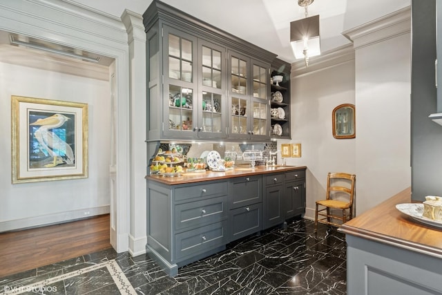 bar area featuring dark marble finish flooring, baseboards, backsplash, and crown molding