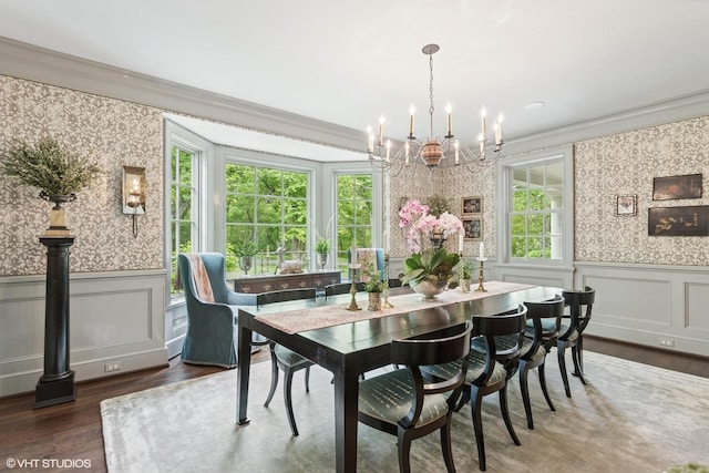 dining space with wallpapered walls, ornamental molding, a chandelier, wood finished floors, and wainscoting
