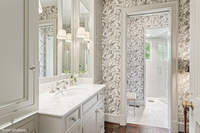 full bath featuring vanity, a shower stall, wallpapered walls, and baseboards