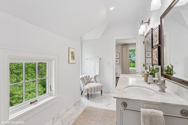 bathroom featuring double vanity, baseboards, vaulted ceiling, and marble look tile flooring