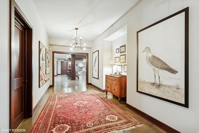 corridor featuring a chandelier and baseboards