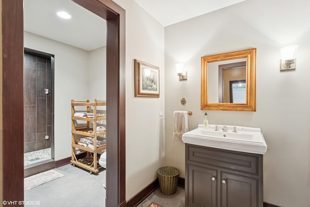 full bathroom with vanity, a tile shower, and baseboards