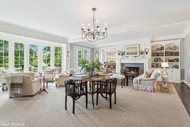dining area with a chandelier, ornamental molding, and a lit fireplace