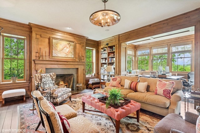 living area featuring wooden walls, light wood-type flooring, healthy amount of natural light, a high end fireplace, and built in features