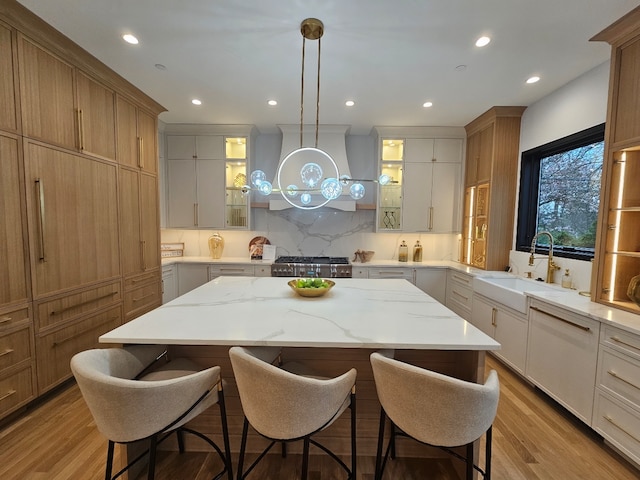 299 Cottage Ave, Glen Ellyn, IL 60137 - kitchen featuring a sink, a kitchen island, a breakfast bar area, glass insert cabinets, and extractor fan