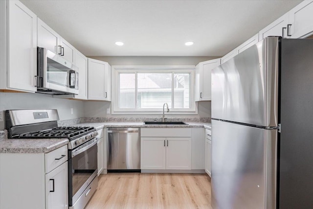 810 N Oak St, Bloomington, IL 61701 - kitchen featuring stainless steel appliances, a sink, light wood-style flooring, white cabinets, and light countertops
