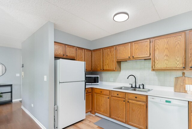 1068 Ashley Ct N Unit 2A, Lockport, IL 60441 - kitchen with white appliances, a sink, light wood-type flooring, light countertops, and backsplash