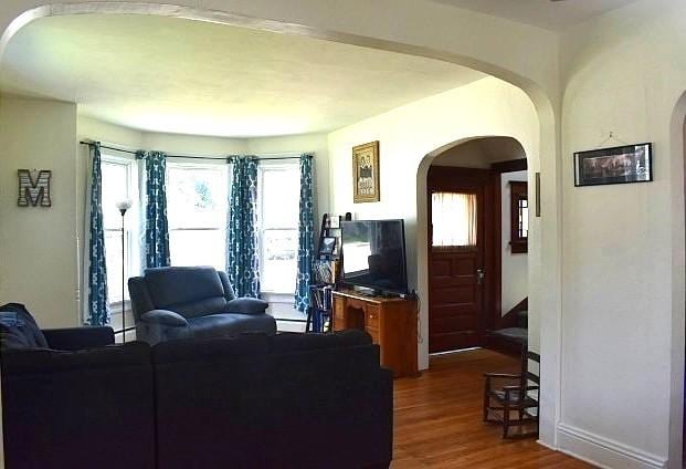 1207 4th Ave, Sterling, IL 61081 - living room featuring arched walkways, dark wood finished floors, and baseboards