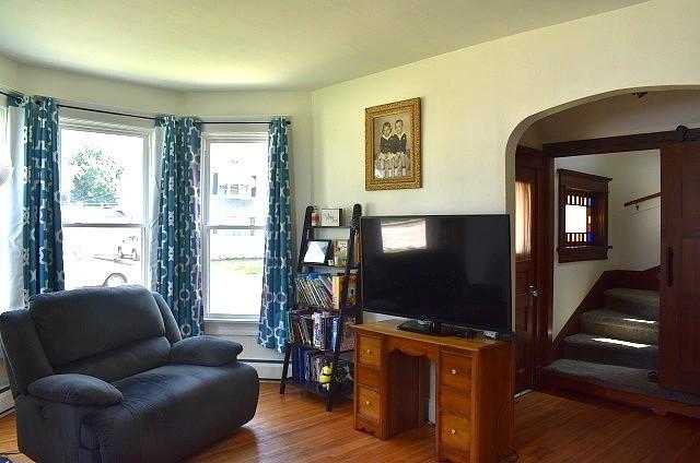 1207 4th Ave, Sterling, IL 61081 - living area with arched walkways, wood finished floors, baseboard heating, and stairway