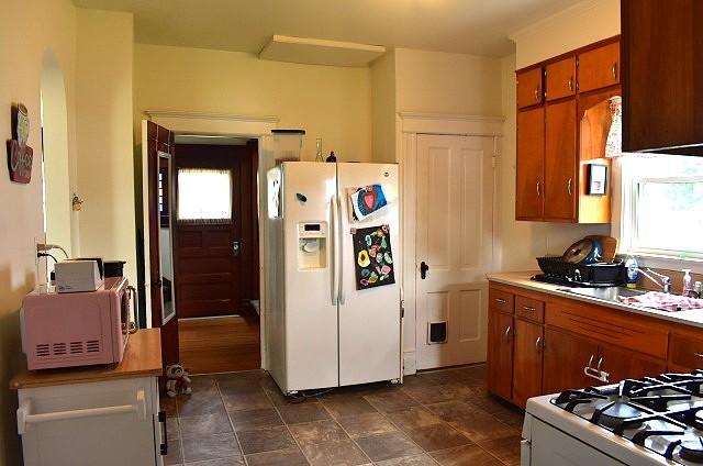 1207 4th Ave, Sterling, IL 61081 - kitchen featuring white appliances, brown cabinetry, a sink, and light countertops