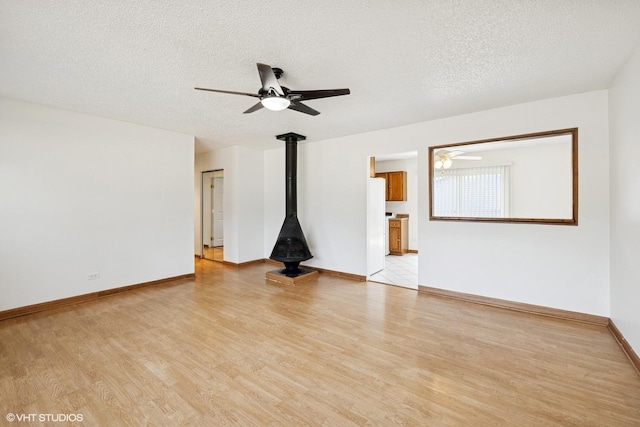 325 Larkdale Row, Wauconda, IL 60084 - unfurnished room featuring a ceiling fan, light wood-style flooring, a wood stove, and a textured ceiling
