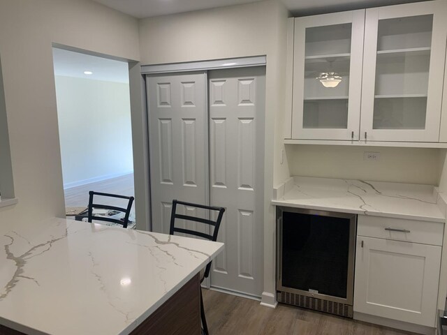 245 Park Ln Unit 208, Palatine, IL 60074 - kitchen featuring wine cooler, white cabinets, dark wood-style flooring, glass insert cabinets, and light stone countertops
