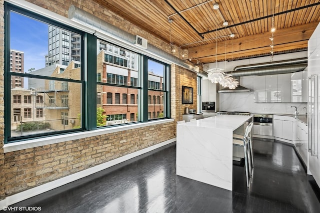 411 W Ontario St Unit 201-302, Chicago, IL 60654 - kitchen featuring brick wall, dark wood-style floors, a center island, white cabinets, and baseboards