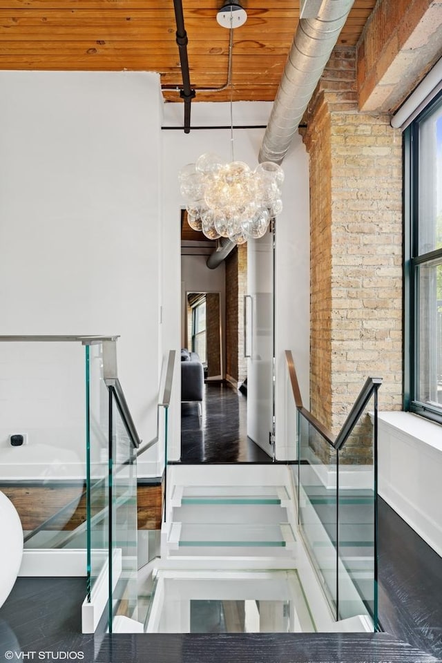 411 W Ontario St Unit 201-302, Chicago, IL 60654 - staircase with a chandelier, brick wall, and wood finished floors