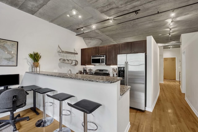 1110 W 15th St Unit 228, Chicago, IL 60608 - kitchen with appliances with stainless steel finishes, a peninsula, a kitchen bar, and light wood finished floors