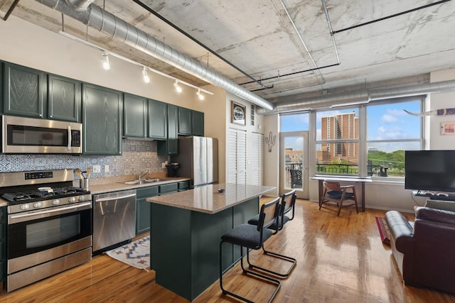 6 S Laflin St Unit 518, Chicago, IL 60607 - kitchen with appliances with stainless steel finishes, light wood-style floors, decorative backsplash, a center island, and a kitchen breakfast bar