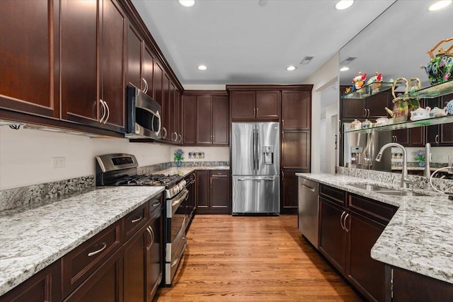 2140 Washington Dr, Northbrook, IL 60062 - kitchen featuring stainless steel appliances, a sink, light stone countertops, dark brown cabinetry, and light wood finished floors
