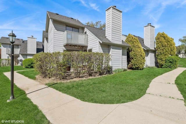 592 Dunham Rd, Gurnee, IL 60031 - view of side of home featuring a balcony, a yard, a chimney, and roof with shingles