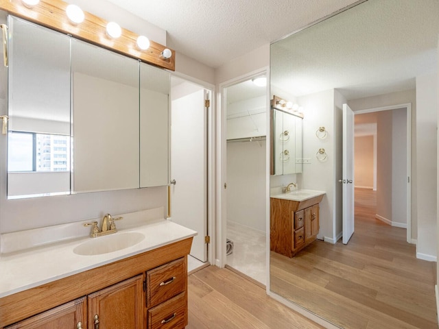 1415 N Dearborn St Unit 25D, Chicago, IL 60610 - full bathroom with wood finished floors, two vanities, baseboards, a textured ceiling, and a walk in closet