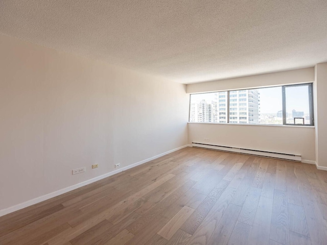 1415 N Dearborn St Unit 25D, Chicago, IL 60610 - spare room with a baseboard heating unit, a textured ceiling, wood finished floors, and baseboards