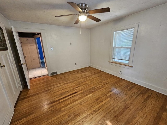 1311 N Neil St, Champaign, IL 61820 - unfurnished bedroom with wood finished floors, baseboards, and a ceiling fan