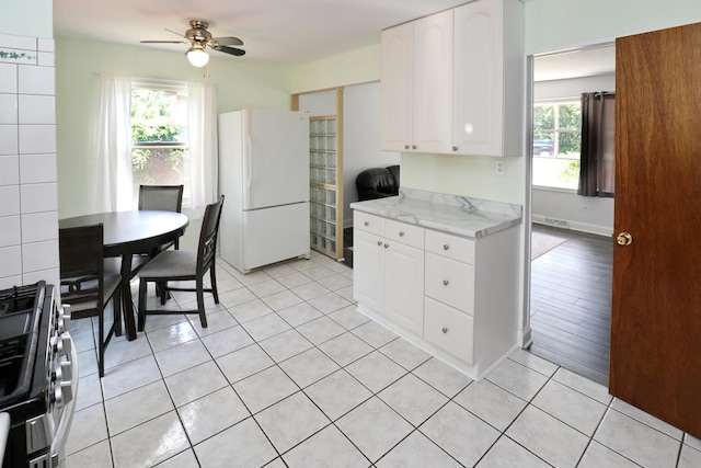 1N485 Neltnor Blvd, West Chicago, IL 60185 - kitchen featuring freestanding refrigerator, stainless steel gas stove, ceiling fan, white cabinets, and light tile patterned flooring