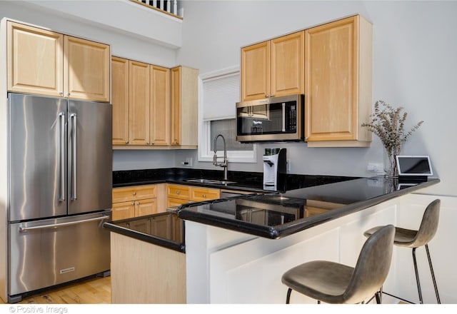 912 W Barry Ave Unit 3, Chicago, IL 60657 - kitchen featuring stainless steel appliances, light brown cabinets, a sink, a peninsula, and a kitchen bar