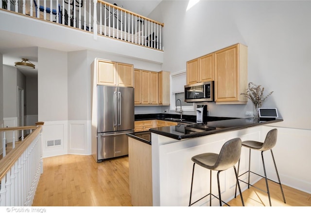 912 W Barry Ave Unit 3, Chicago, IL 60657 - kitchen with appliances with stainless steel finishes, light brown cabinetry, a sink, a high ceiling, and a peninsula