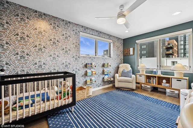 1233 N Paulina St Unit 3N, Chicago, IL 60622 - bedroom with multiple windows, wood finished floors, a crib, wallpapered walls, and a ceiling fan