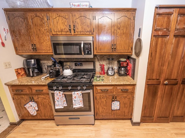 601 Fairlane Dr, Joliet, IL 60435 - kitchen featuring appliances with stainless steel finishes, tasteful backsplash, light wood-style flooring, and brown cabinetry