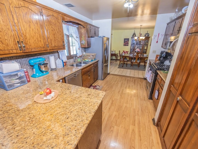 601 Fairlane Dr, Joliet, IL 60435 - kitchen featuring appliances with stainless steel finishes, light wood-style floors, a chandelier, brown cabinets, and tasteful backsplash