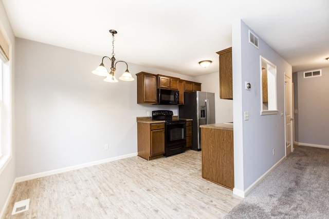 2521 Fox Trot Trl, Bloomington, IL 61705 - kitchen featuring black appliances, a chandelier, baseboards, light countertops, and light wood-style floors
