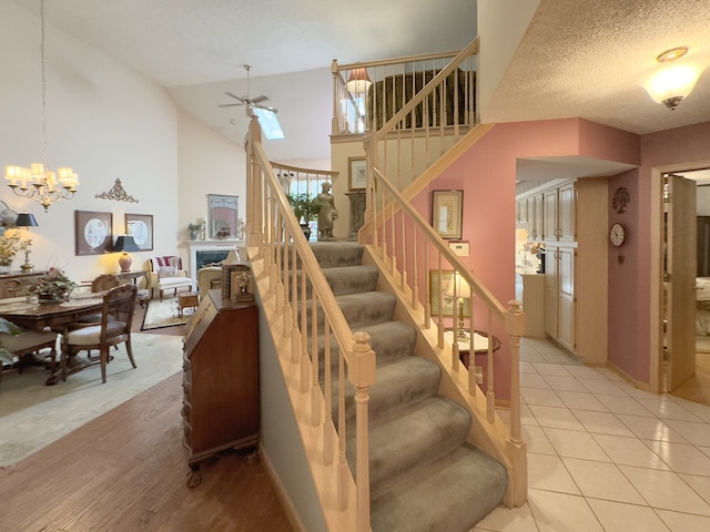503 Shagbark Dr Unit 503, Elgin, IL 60123 - stairs featuring ceiling fan, a fireplace, a chandelier, high vaulted ceiling, and tile patterned floors
