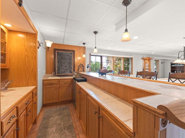 18210 W Winds Ln, Orland Park, IL 60467 - kitchen with tile countertops, brown cabinetry, hanging light fixtures, a paneled ceiling, and a sink