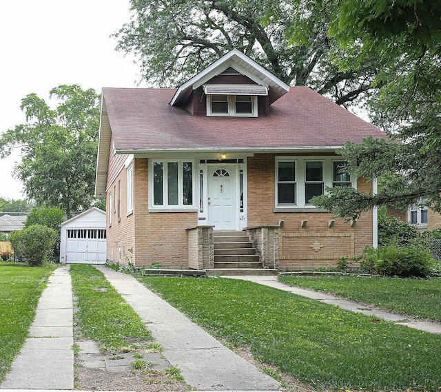 bungalow with concrete driveway, an outdoor structure, a detached garage, a front yard, and brick siding