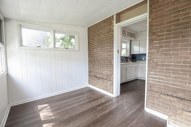 spare room with dark wood finished floors and brick wall