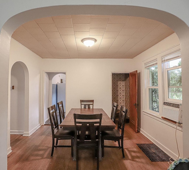 dining space with wood finished floors, arched walkways, and cooling unit