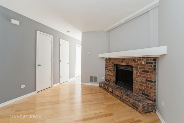 410 Kensington Ct Unit 410, Naperville, IL 60563 - unfurnished living room featuring light wood-type flooring, a brick fireplace, and baseboards