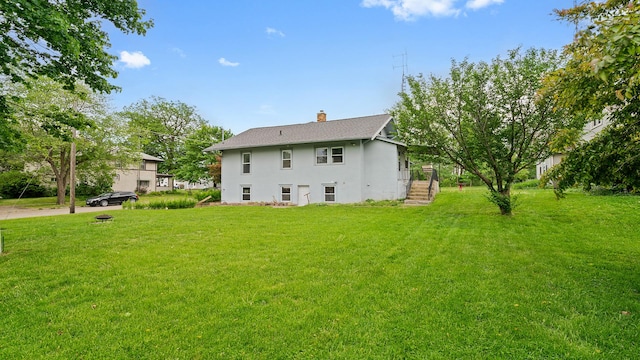 110 E Center St, Mount Morris, IL 61054 - rear view of property with stucco siding, a chimney, and a yard