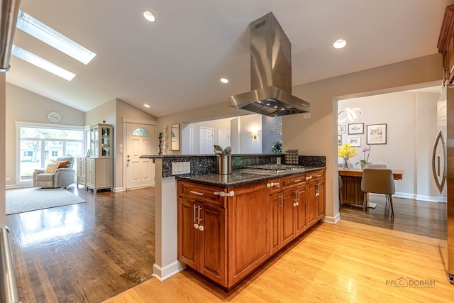 826 Midway Rd, Northbrook, IL 60062 - kitchen with island exhaust hood, a skylight, a peninsula, brown cabinetry, and dark stone counters