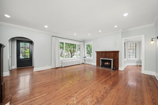 734 Forest Rd, La Grange Park, IL 60526 - unfurnished living room with radiator heating unit, arched walkways, a fireplace with flush hearth, wood finished floors, and ornamental molding