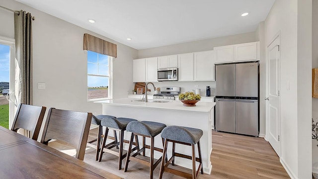 13603 S Carmel Blvd, Plainfield, IL 60544 - kitchen featuring appliances with stainless steel finishes, a sink, an island with sink, light wood finished floors, and light countertops