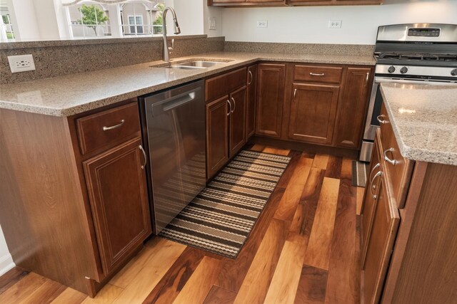 552 Autumn Cir, Pingree Grove, IL 60140 - kitchen featuring stainless steel appliances, light wood-style floors, a sink, light stone countertops, and a peninsula