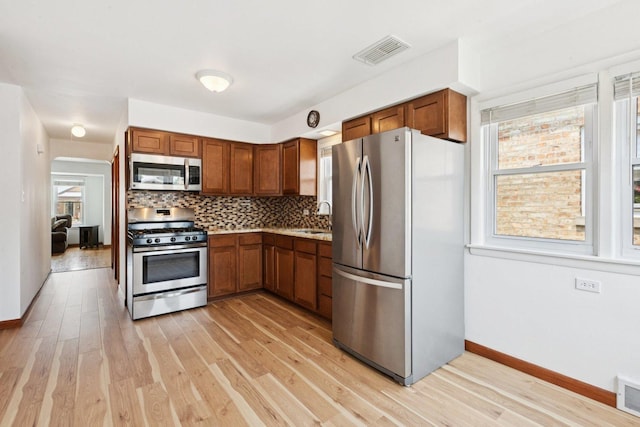 5423 S Rutherford Ave, Chicago, IL 60638 - kitchen with stainless steel appliances, light wood-style flooring, tasteful backsplash, brown cabinets, and light countertops