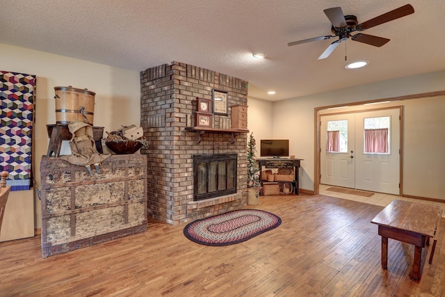 611 Marsha Ln, Rock Falls, IL 61071 - living room with wood finished floors, a brick fireplace, a ceiling fan, a textured ceiling, and baseboards