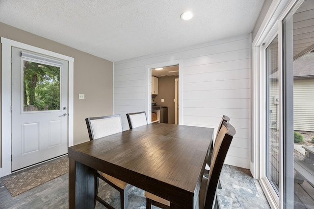 7308 W Lancaster Rd, Peoria, IL 61607 - unfurnished dining area with a textured ceiling, wood walls, and washing machine and clothes dryer
