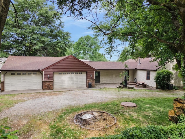 7308 W Lancaster Rd, Peoria, IL 61607 - ranch-style home with a fire pit, dirt driveway, brick siding, a garage, and a front lawn
