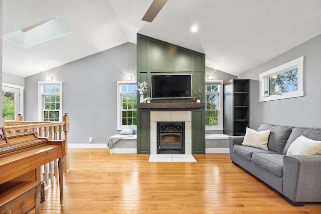 7308 W Lancaster Rd, Peoria, IL 61607 - living room featuring vaulted ceiling, light wood-style floors, a skylight, plenty of natural light, and a large fireplace