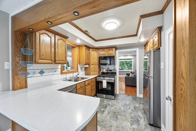 7308 W Lancaster Rd, Peoria, IL 61607 - kitchen with appliances with stainless steel finishes, a sink, a peninsula, brown cabinets, and light countertops