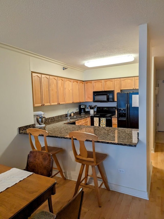 512 N Mcclurg Ct Unit 512, Chicago, IL 60611 - kitchen featuring black appliances, light brown cabinets, a peninsula, a textured ceiling, and light wood-type flooring